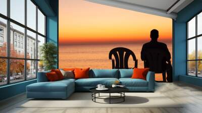 Man sits on chair alone in sunset Wall mural