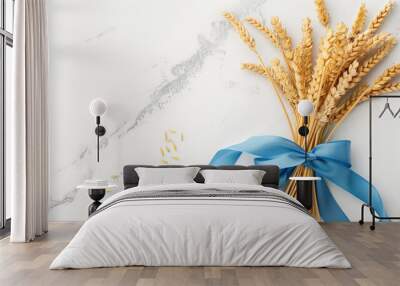 Bouquet of wheat with blue ribbon on white marble background, top view, copy space. Wall mural