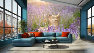 A bottle of champagne and glasses in a sunset lavender field. Wall mural