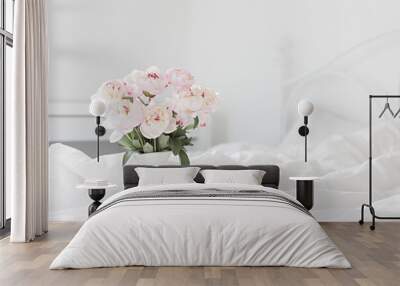 Bouquet of pink peonies on white bed linen. Modern interior in the bedroom. Wedding and festive style. Wall mural