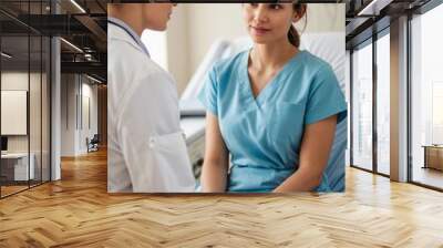 A female doctor sits beside a patient, providing comfort and care in a hospital setting. Wall mural