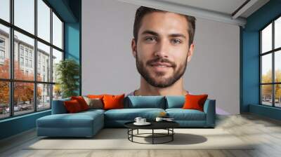 Portrait of a young man with a confident smile. Studio shot with neutral background. Wall mural