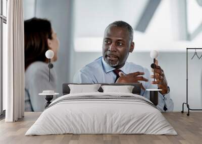 Businessman explaining to businesswoman in meeting Wall mural