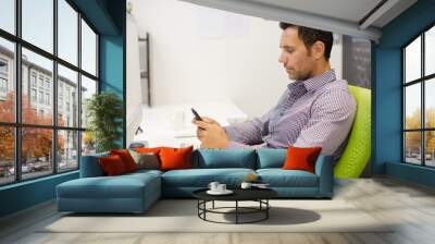 Businessman using cell phone at desk in office Wall mural