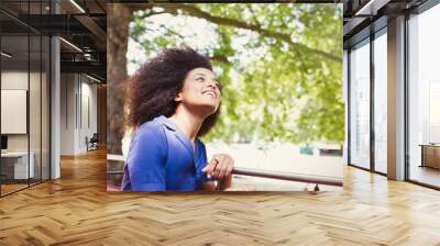 Carefree woman with afro riding double decker bus and looking up Wall mural