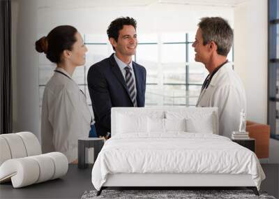 Doctor and businessman handshaking in hospital lobby Wall mural