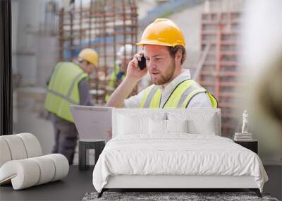 Engineer digital tablet talking on cell phone at construction site Wall mural