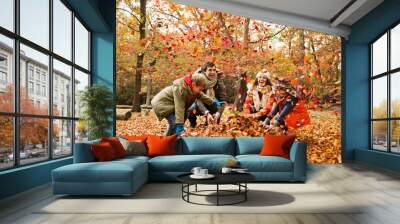 Family playing in autumn leaves Wall mural