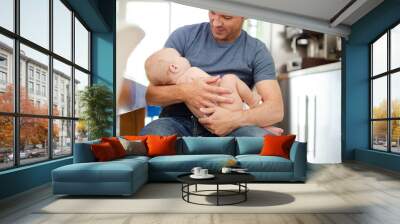 Father holding baby in kitchen Wall mural