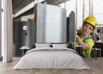 Female steel worker examining steel part in factory Wall mural