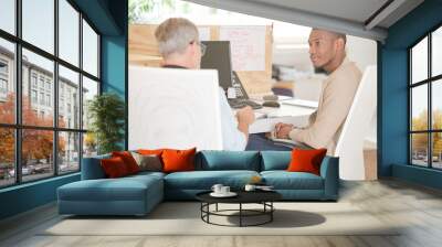 Men sitting at desk in office and talking Wall mural