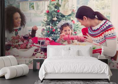 Mother and daughter pulling Christmas cracker at dinner Wall mural