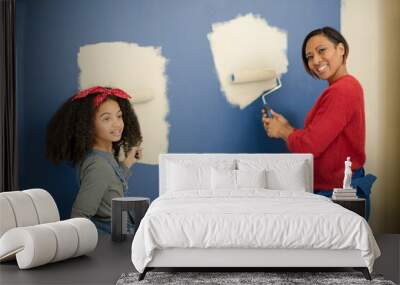 Portrait happy mother and daughter
with paint rollers painting room Wall mural