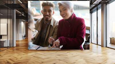 Portrait of smiling friends eating at restaurant outdoor patio Wall mural