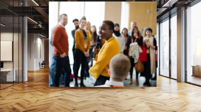 Smiling female speaker with microphone on stage Wall mural