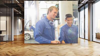 Smiling mechanics using computer in auto repair shop Wall mural