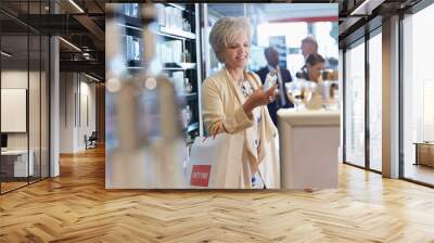 Smiling woman shopping for perfume in duty free shop Wall mural