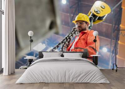 Steel worker holding crane chain in factory Wall mural