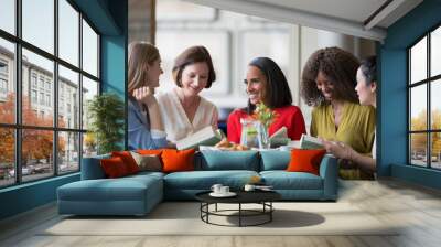 Women friends discussing book club book at restaurant table Wall mural