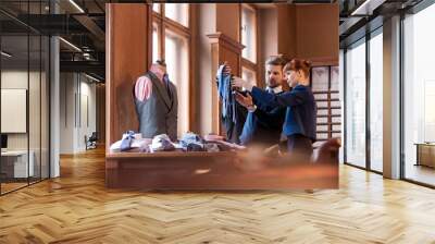 Worker showing ties to businessman in menswear shop Wall mural