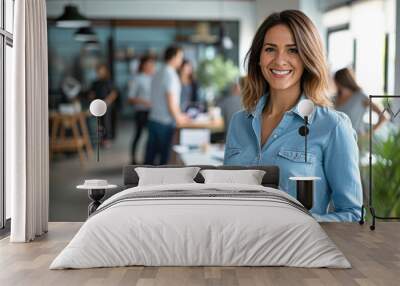 A business woman wearing a blue shirt stands in her office with his tablet. Wall mural