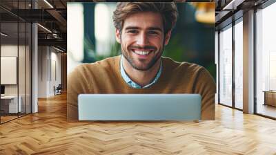 A man is sitting at a desk with a laptop in front of him Wall mural