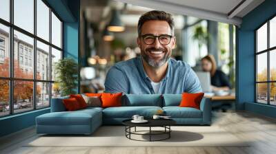 A man wearing glasses and a blue shirt is smiling for the camera Wall mural