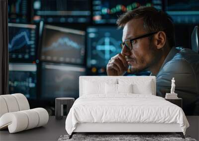 A man wearing glasses is looking at a computer screen with multiple monitors Wall mural