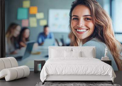 A woman is smiling and sitting at a desk with a group of people Wall mural