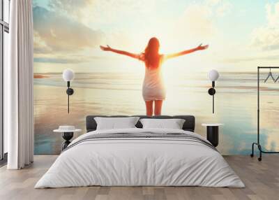 A woman is standing on the beach with her arms outstretched Wall mural