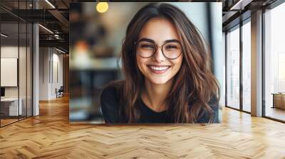 A woman with glasses is smiling and looking at the camera Wall mural