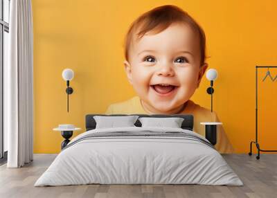 baby smiling and looking up to camera on a yellow background Wall mural