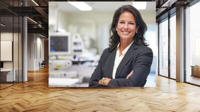 Confident female healthcare executive standing in a hospital with medical equipment in the background. Wall mural