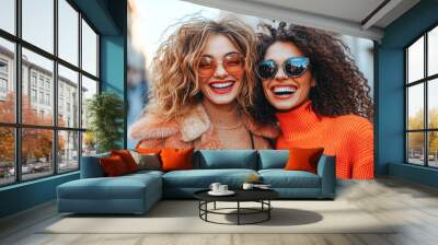 Two women with curly hair and sunglasses are smiling and posing for a picture Wall mural