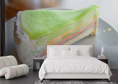 Colorful Rainbow Crepes Cake with Berry Sauce in white plate on wooden table background with copy space. Wall mural