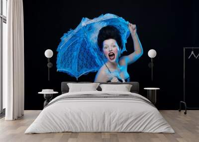 emotional actress brunette woman in an ancient medieval attire and lush hair with white feathers with a white lace umbrella in hand on a black background in the studio Wall mural