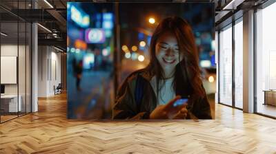 Smiling beauty asian woman model 20s using cell phone on a city street at night Wall mural