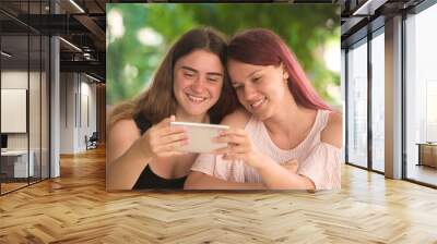 Two young girls read messages in a smartphone Wall mural