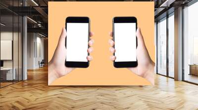 two hands holding smart phones on  yellow background with clipping path Wall mural