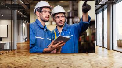 Mechanic and staff engineer talking nearby a machine in a big factory about latest new planing, Two men engineer talking in modern factory. Wall mural