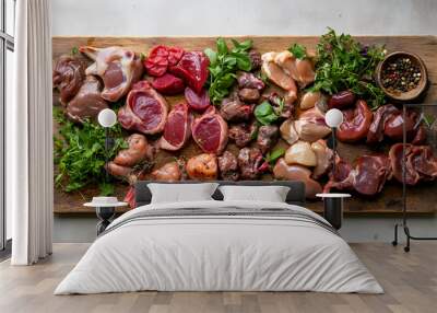 assortment of raw organ meats, including lamb hearts and chicken livers, arranged on a cutting board Wall mural