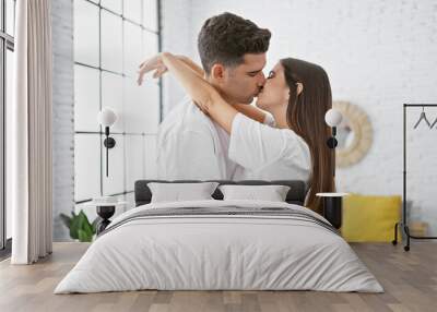 A man and woman embracing in a romantic gesture in a well-lit modern bedroom at home. Wall mural