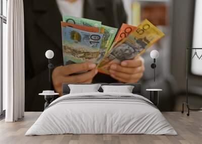 A professional woman holds australian currency in a modern office, depicting finance and workplace themes. Wall mural