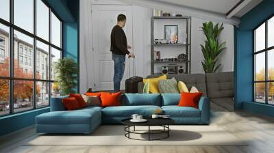 A young hispanic man with luggage in a modern living room ready to depart Wall mural