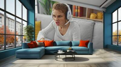 A young woman in casual attire intensely playing a video game in her modern living room. Wall mural