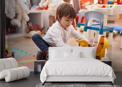 Adorable caucasian boy playing with tools toy sitting on floor at kindergarten Wall mural