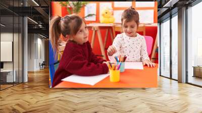 Adorable girls preschool students sitting on table drawing on paper at kindergarten Wall mural