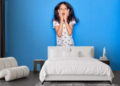 Adorable hispanic child girl wearing casual clothes smiling happy. Jumping with smile on face over isolated blue background Wall mural