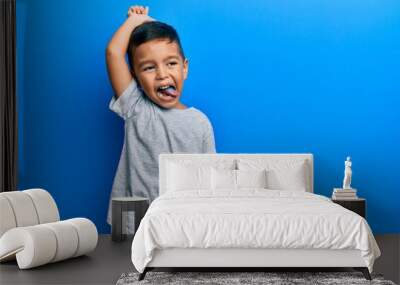 Adorable latin toddler showing blue tongue standing over isolated background. Wall mural