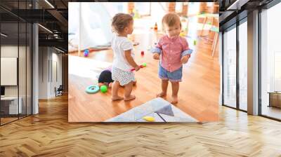 Adorable toddlers playing around lots of toys at kindergarten Wall mural